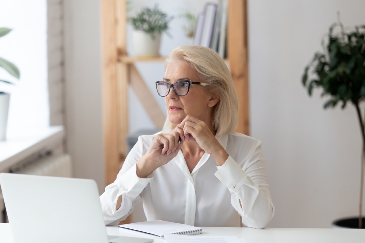 Serious senior woman with laptop and notepad