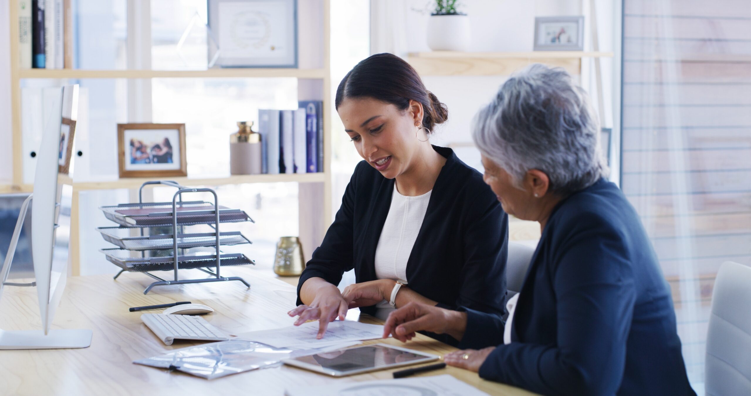 Financial planner looking at paperwork and a tablet with a female client
