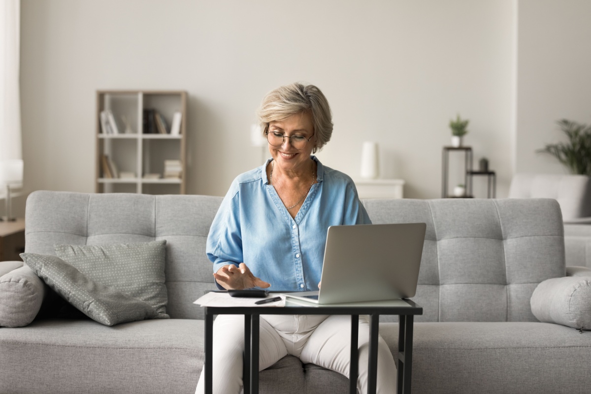 Happy middle-aged woman using a calculator and laptop