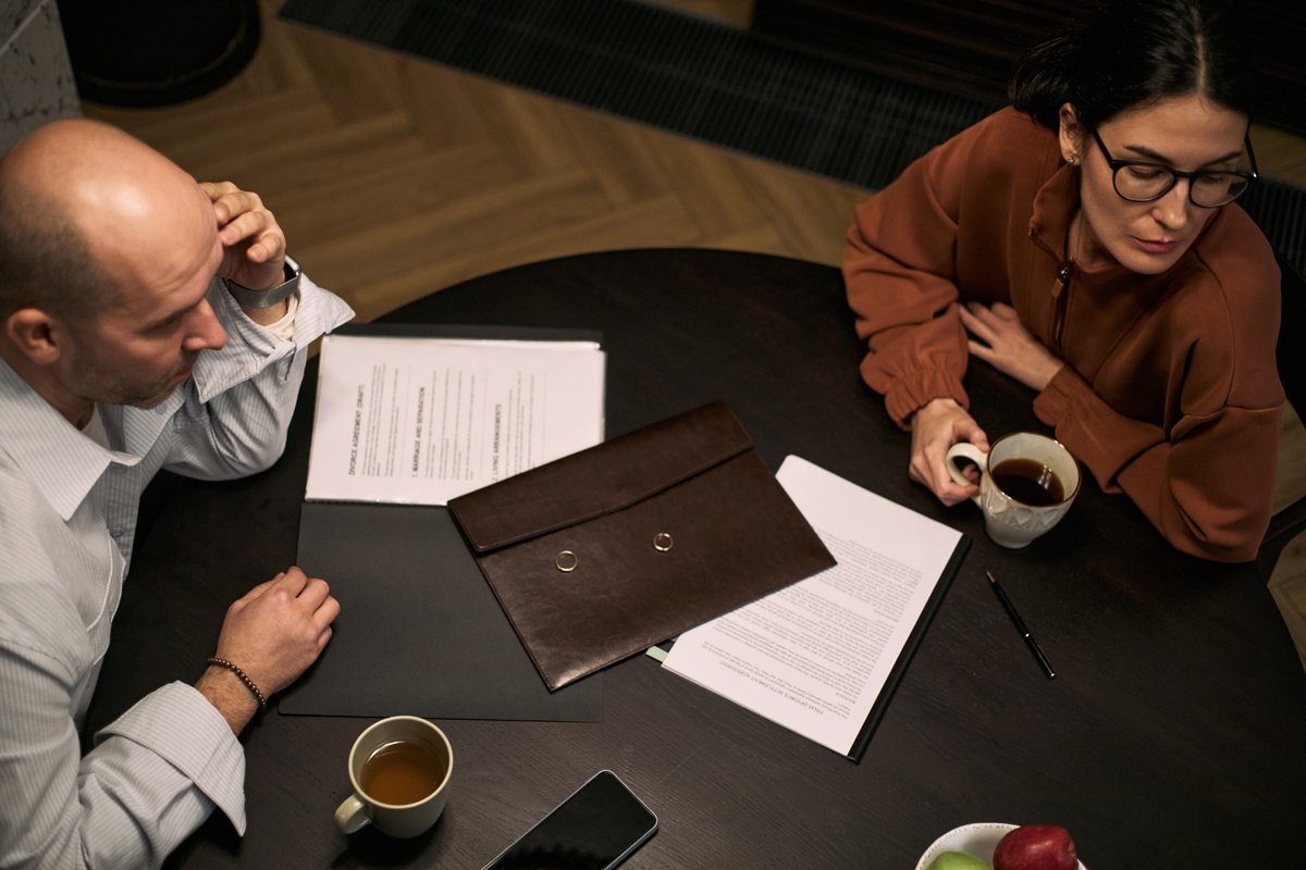 Middle-aged couple with divorce papers sitting apart in conflict